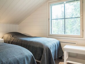 Een kamer met twee bedden, een raam en een witte tafel.