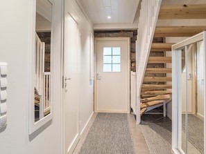 Un pasillo con una escalera de madera, una puerta con ventanal y una alfombra con textura.