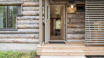 A log cabin entrance with a wooden door, a set of steps leading up to the door, and a small porch area.