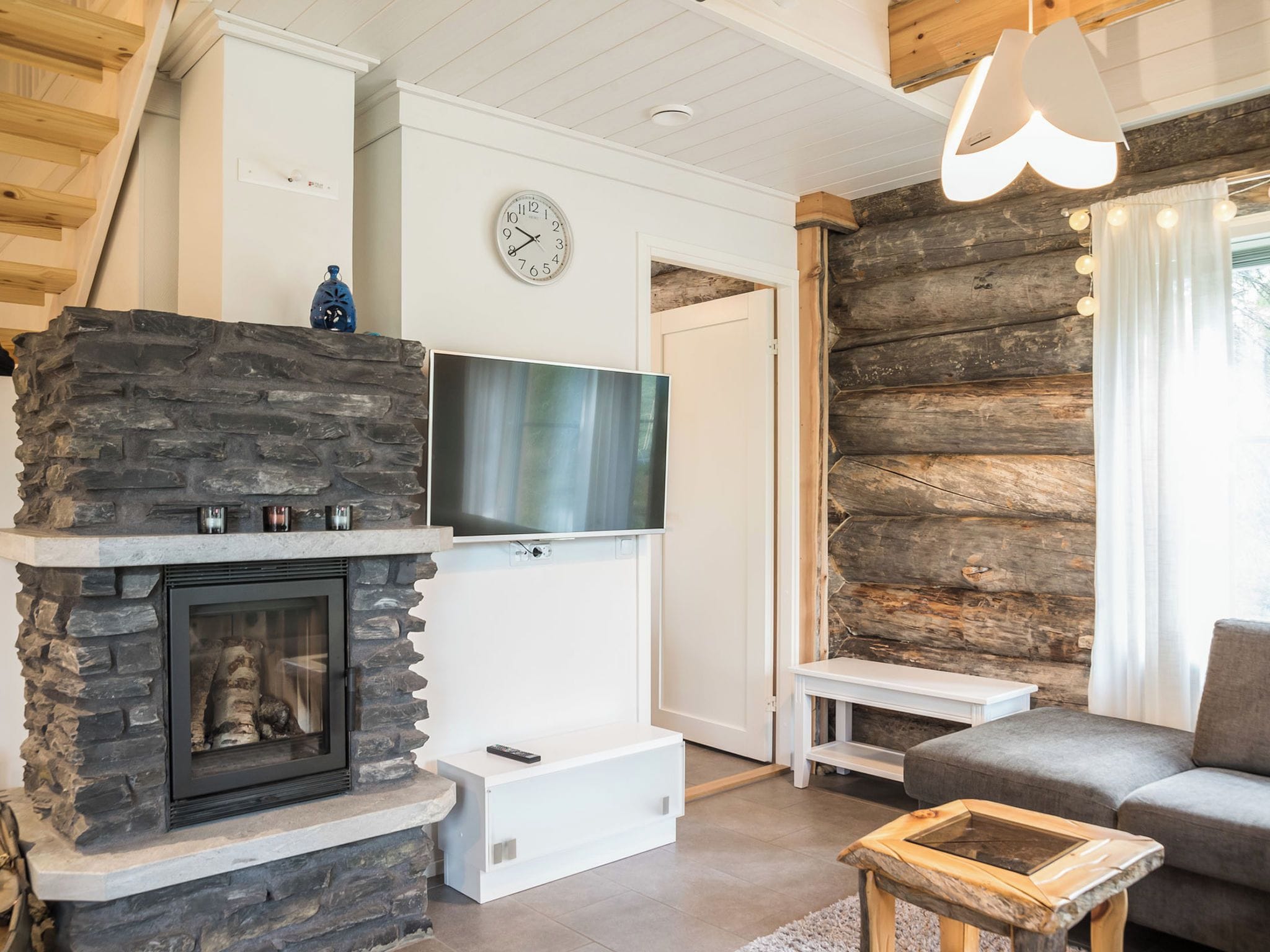 A modern living room with a stone fireplace, a flat-screen TV, and a cozy seating area.