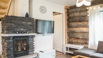 A modern living room with a stone fireplace, a flat-screen TV, and a cozy seating area.