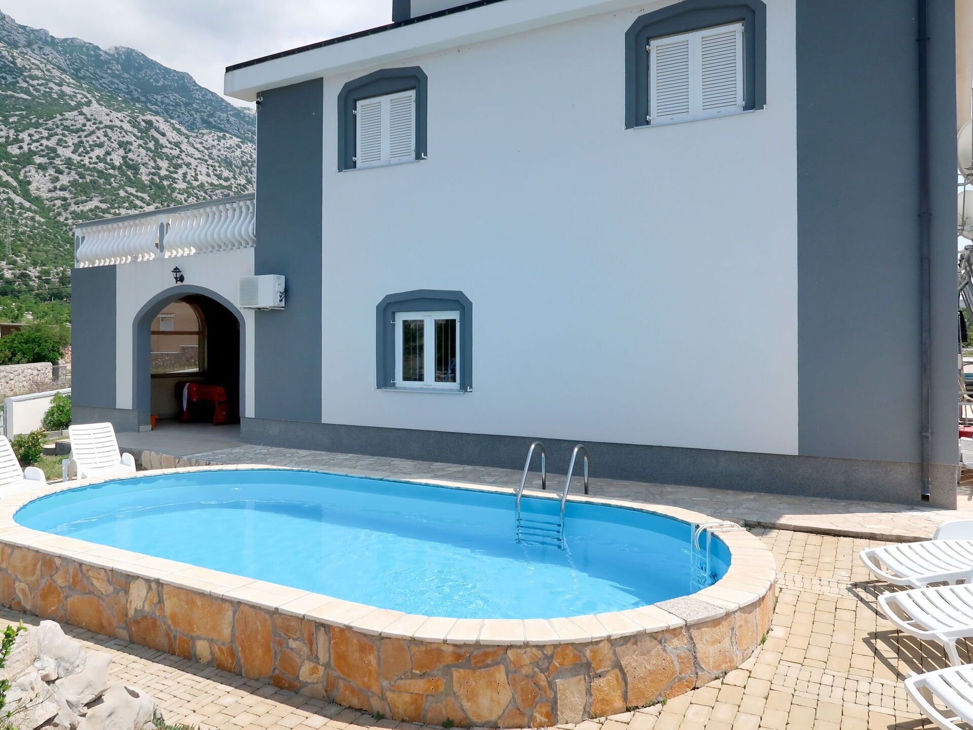 En modern byggnad med en swimmingpool, stenmurar och en bergskedja i bakgrunden.