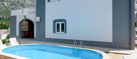 En modern byggnad med en swimmingpool, stenmurar och en bergskedja i bakgrunden.