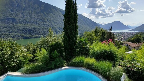 Une piscine entourée d’une végétation luxuriante, avec des montagnes en arrière-plan.