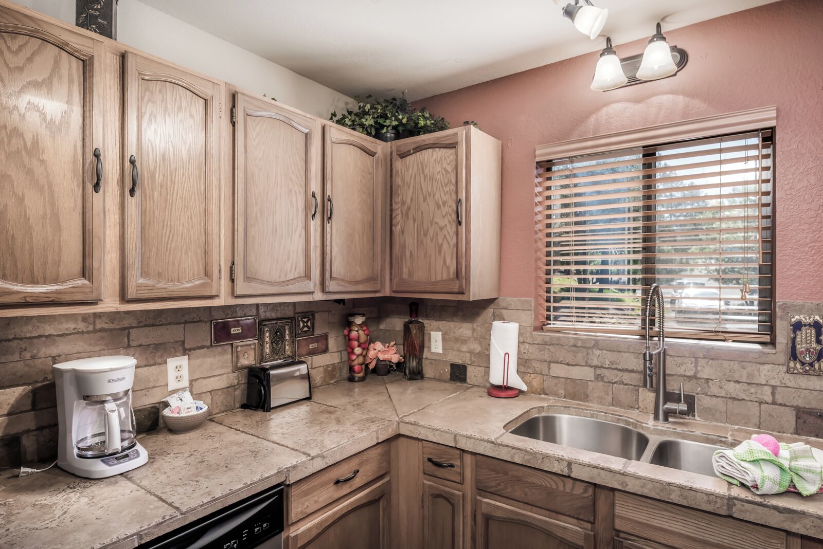 A kitchen with wooden cabinets, a built-in oven, a coffee maker, and a sink.
