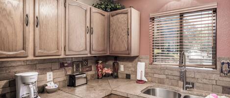 A kitchen with wooden cabinets, a built-in oven, a coffee maker, and a sink.