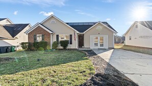 A single-story house with a front yard, a driveway, and a solar panel on the roof. - Cozy Home for Entire Family (Charlotte)