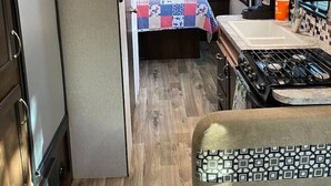 A compact RV kitchen with a stove, microwave, and sink.