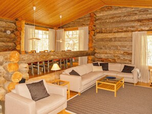 L'intérieur d'une cabane en rondins, avec un canapé, une table basse et un coin repas.
