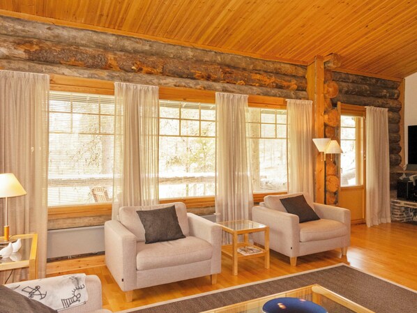 A log cabin interior with two sofas, a coffee table, and a fireplace.