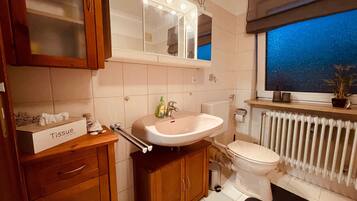 Un bagno con lavandino, WC, specchio e finestra.