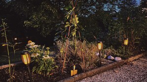 Un sendero de jardín con faroles decorativos, plantas y un borde de grava.