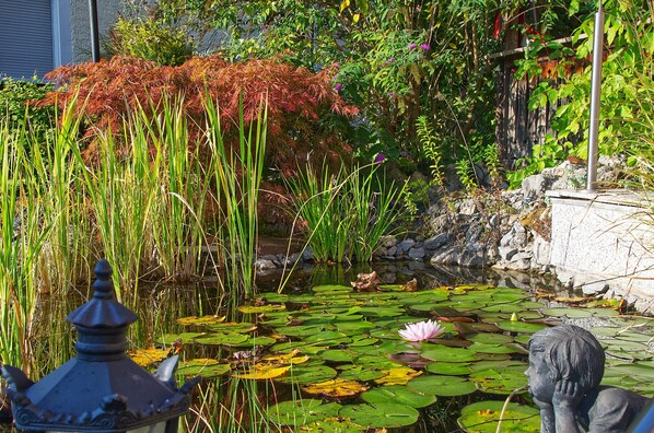A pond with lily pads and a statue in the foreground.