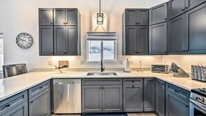 Una cucina moderna con mobili grigi, elettrodomestici in acciaio inossidabile e una grande finestra che si affaccia su un paesaggio innevato.