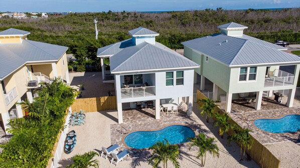 A residential complex with multiple houses, a swimming pool, and a fenced patio area.