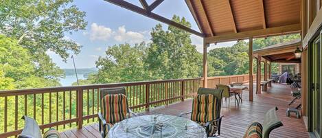 A covered outdoor deck with a table and chairs, overlooking a scenic landscape.