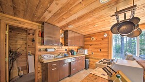Cocina de cabaña de madera con interior de madera, un lavamanos, armarios, un microondas y una estufa.
