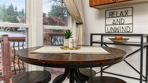 A round dining table with a placemat, a small potted plant, and two candles on a balcony with a view of trees and a street. - Captivating and Charming Retreat, Game Rooms, Pool Table, Foosball, 20 Min to Portland (West Linn)