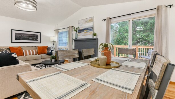 A dining area with a wooden table, chairs, and a view of the outdoors through large windows. - Captivating and Charming Retreat, Game Rooms, Pool Table, Foosball, 20 Min to Portland (West Linn)