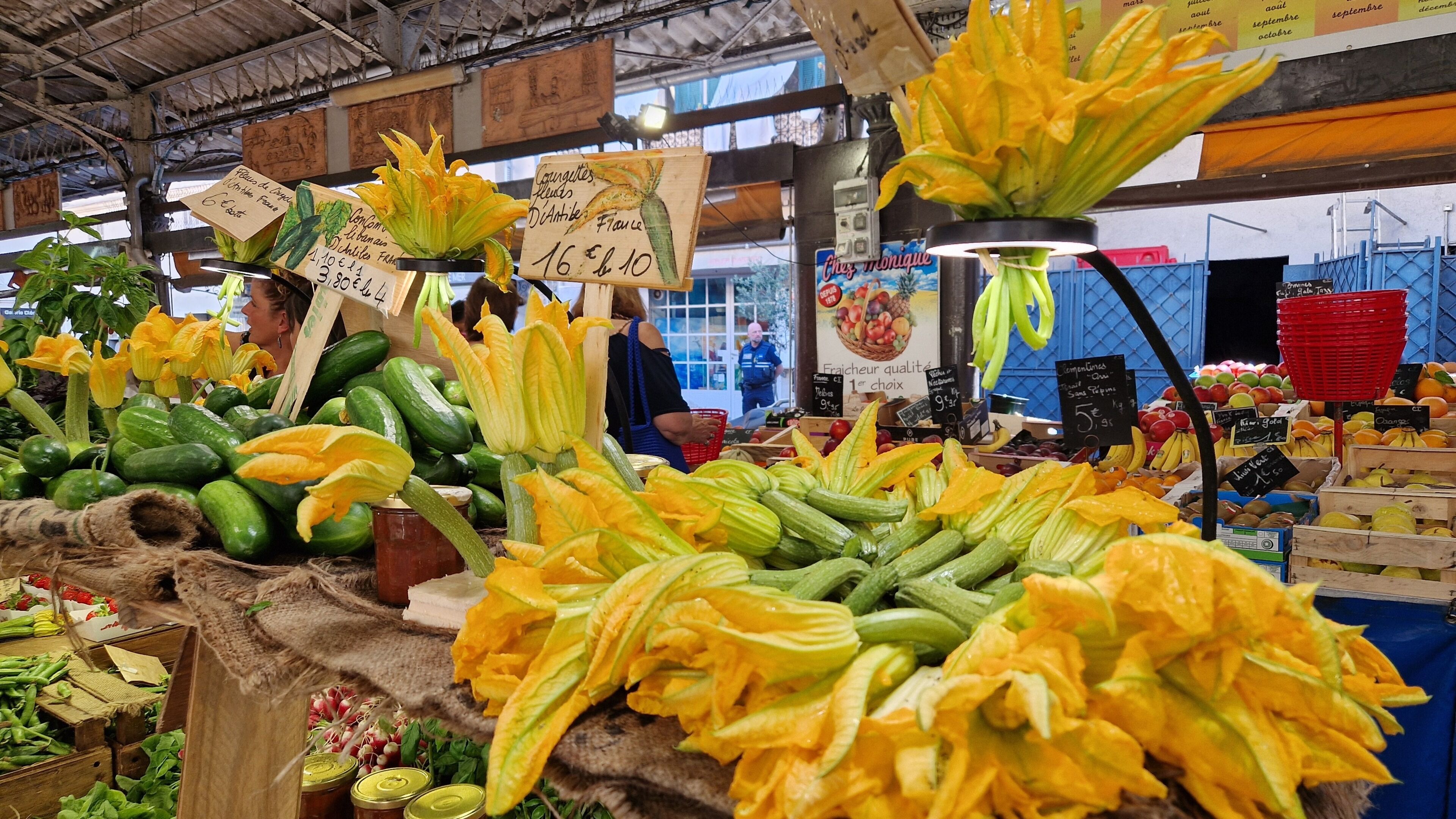 A market stall with various vegetables and flowers on display.