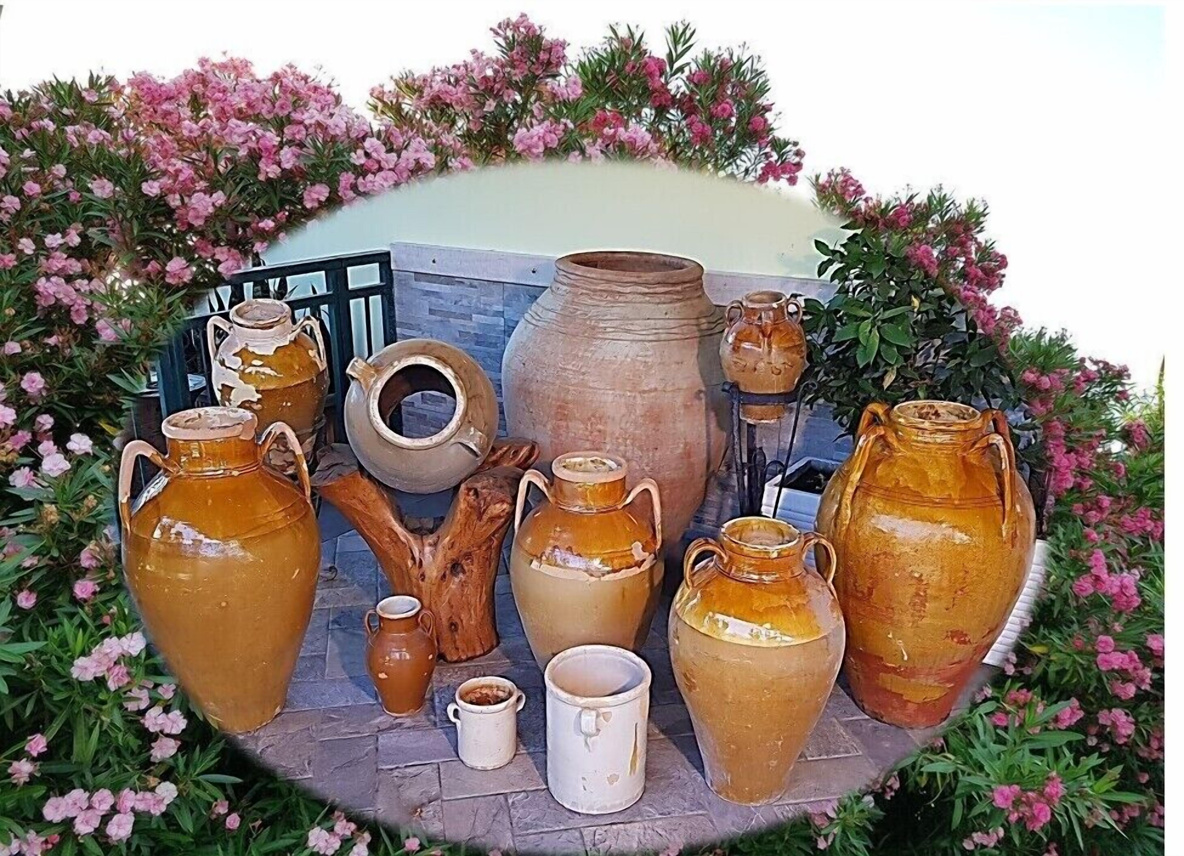 Une collection de poteries et une structure en bois rustique, le tout entouré de fleurs roses.