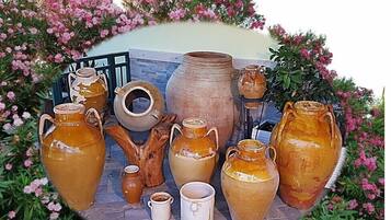 Une collection de poteries et une structure en bois rustique, le tout entouré de fleurs roses.