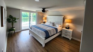 Ein Schlafzimmer mit einem großen Bett, einem Deckenventilator, zwei Nachttischlampen und einem Topfpflanzen.