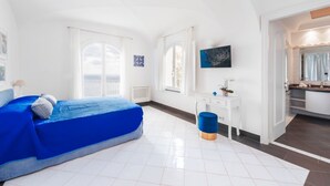 Ein Zimmer mit einem Bett, einem Schreibtisch, einem Stuhl und einem durch eine offene Tür einsehbaren Badezimmer.