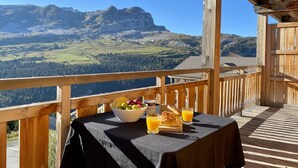 A wooden deck with a table set for breakfast, overlooking a mountainous landscape. - South-facing panoramic mountain view - T2 ski in, Pool & Spa (FLAINE, Arâches-la-Frasse)