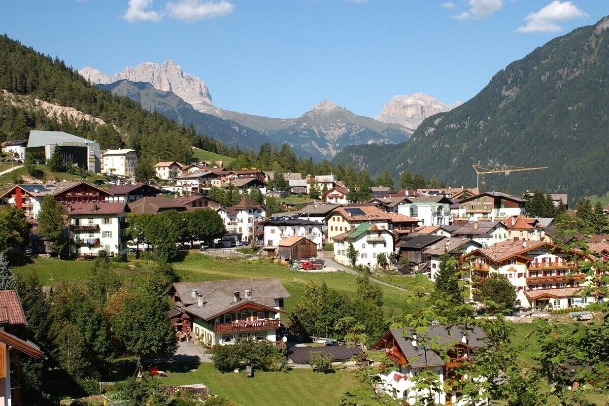 A mountain village with traditional architecture, a ski lift, and a view of the surrounding mountains.