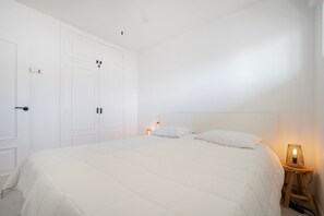 A bedroom with a large bed, a wooden nightstand, and a white wardrobe. - Apartment "Costabella Altea" with Mountain View, Pool, Wi-Fi, Garden & Terrace (Altea)