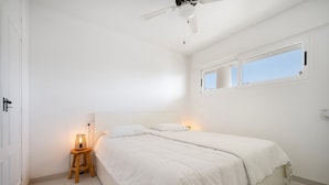 A minimalist bedroom with a single bed, a nightstand, a ceiling fan, and a window with a view. - Apartment "Costabella Altea" with Mountain View, Pool, Wi-Fi, Garden & Terrace (Altea)