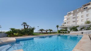 A swimming pool with a clear blue water surface, surrounded by a landscaped area with palm trees and shrubs. - Apartment "Costabella Altea" with Mountain View, Pool, Wi-Fi, Garden & Terrace (Altea)