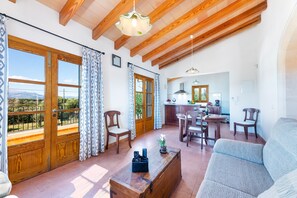 A spacious living area with wooden beams, a dining table, chairs, and a sofa.