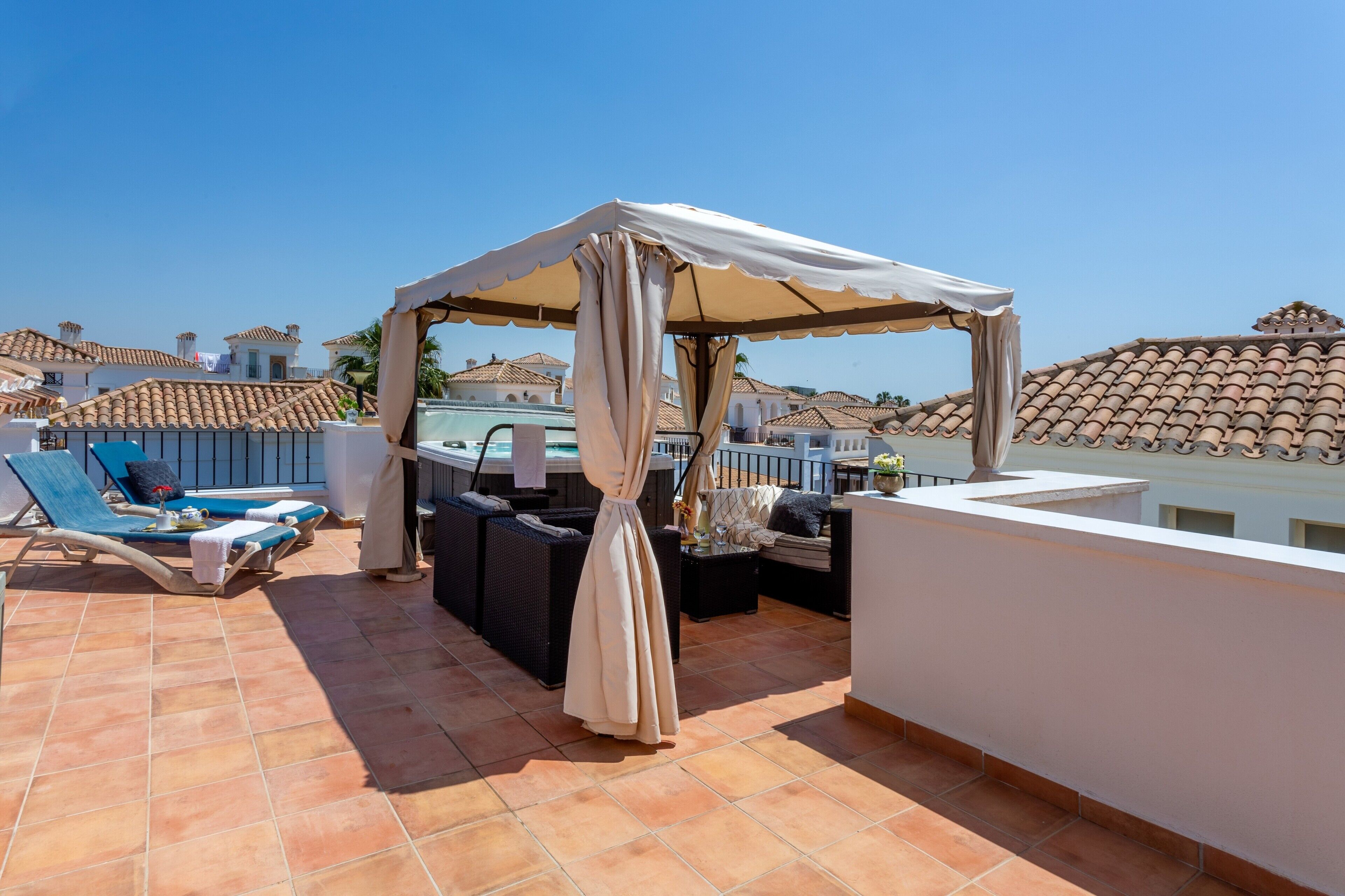 Una terraza en la azotea con sillones de descanso, un área de estar cubierta y vistas a edificios vecinos.
