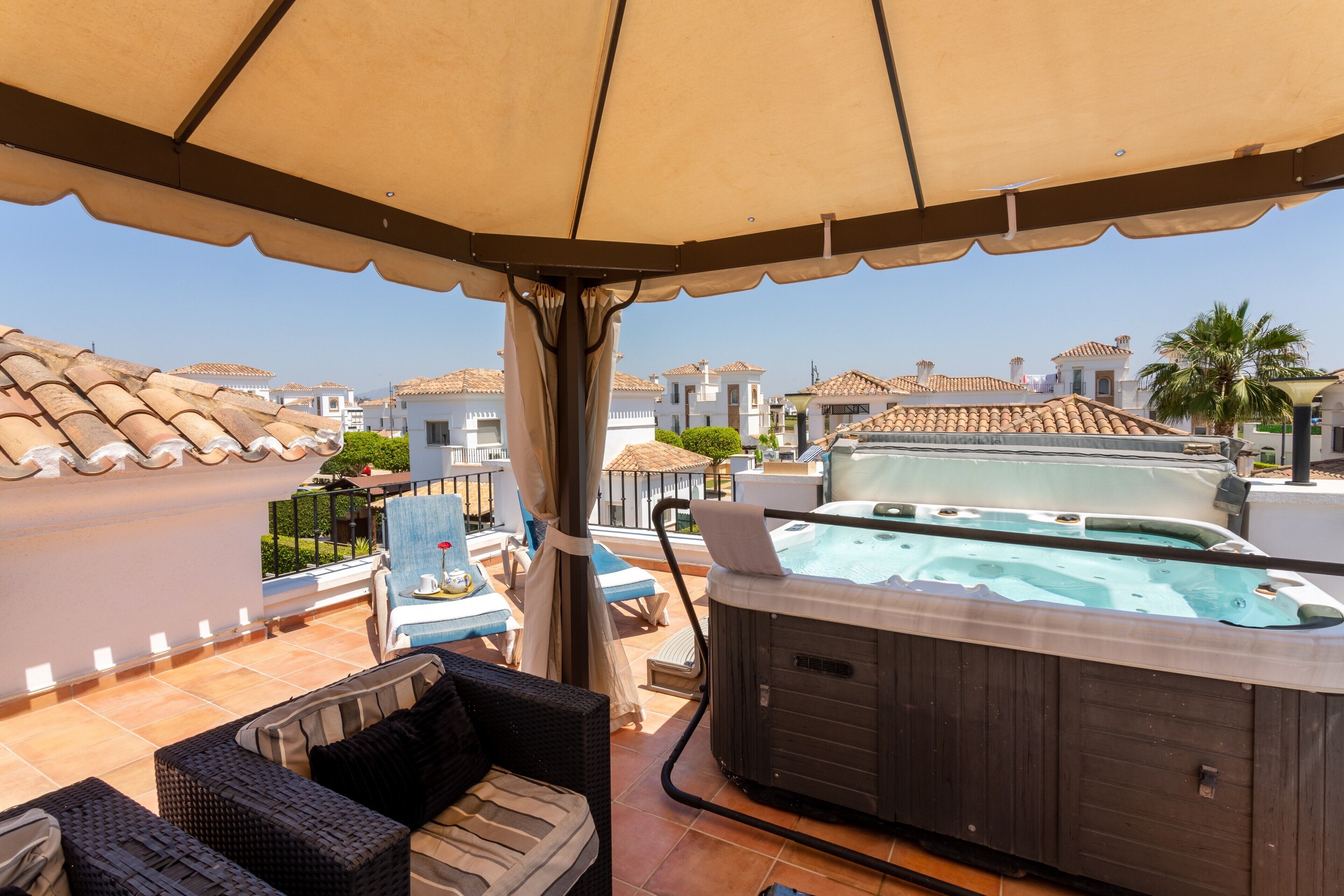 Terraza en la azotea con jacuzzi, mobiliario exterior y vistas a edificios cercanos.
