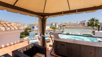 Terraza en la azotea con jacuzzi, mobiliario exterior y vistas a edificios cercanos.