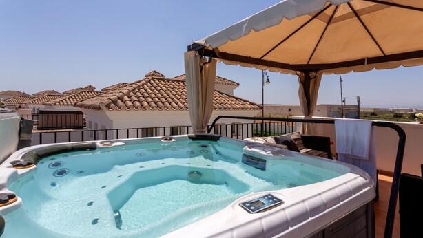 Un jacuzzi sur un balcon avec vue sur les immeubles.