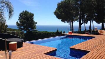 Een infinity pool, ligstoelen bij het zwembad