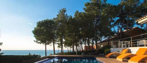 Een infinity pool, ligstoelen bij het zwembad