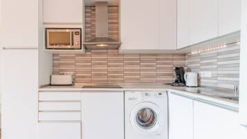 Een kleine keuken met een magnetron, broodrooster en wasmachine.