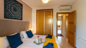 Habitación de hotel con cama, almohadas, una bandeja con artículos de aseo, toalla y un armario de madera.