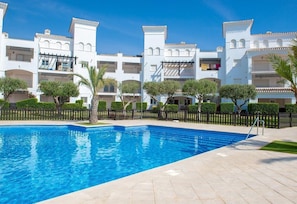 A swimming pool with a tiled deck, surrounded by white buildings with balconies and a fence. - Apartment "Luxury Pool and Spa - Casa Coco" with Pool, Whirlpool & Terraces (La Torre Golf Resort)