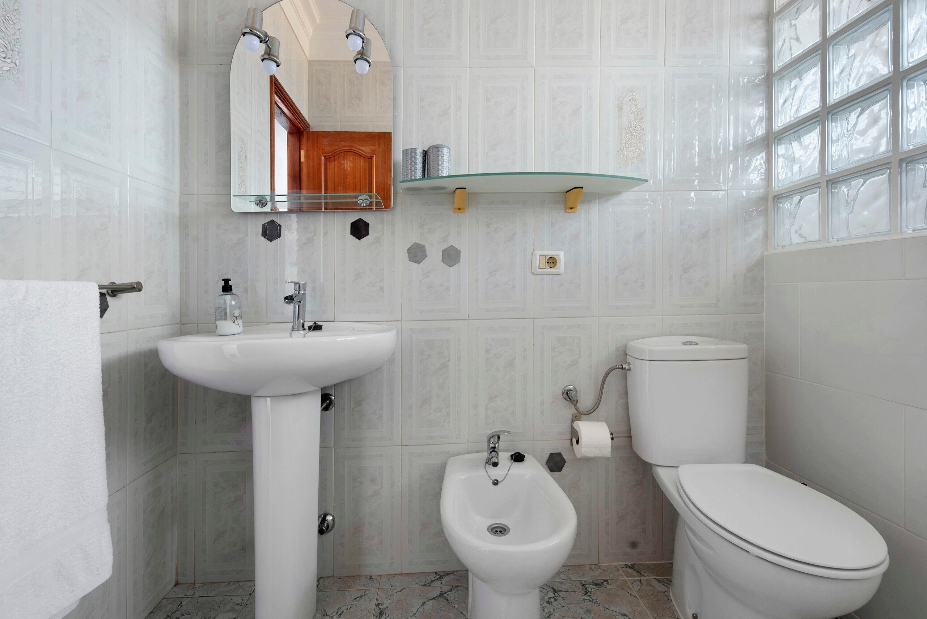 Une salle de bain équipée d’un lavabo, d’un bidet, de toilettes et d’un miroir au-dessus du lavabo.