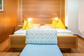 A wooden bed with a headboard, two bedside tables, and a bench.