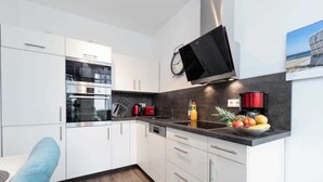 A modern kitchen with white cabinets, stainless steel appliances, and a black countertop.