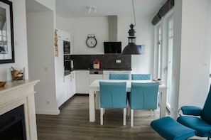 Une cuisine moderne avec des meubles blancs, une horloge noire et un luminaire suspendu.