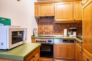 Une cuisine dotée de meubles de rangement en bois, d’un four à micro-ondes, d’un four traditionnel et d’un lave-vaisselle.
