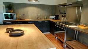 A modern kitchen with a wooden island, stainless steel appliances, and a large window.