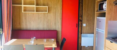A compact kitchen with a wooden countertop, a red door, and a built-in microwave.